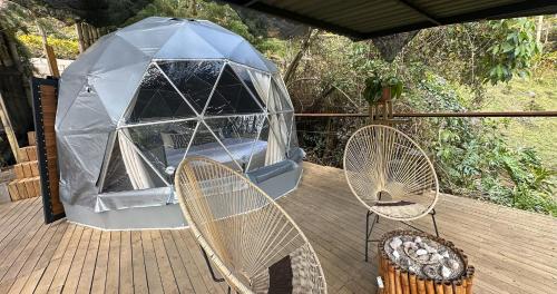 a gazebo with two chairs on a deck at Omghat Glamping - Domo Sarasvasti in El Peñol