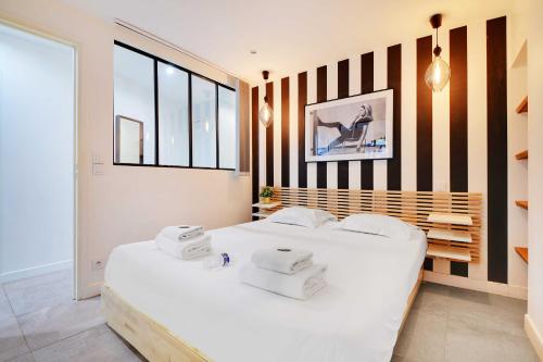 - une chambre avec 2 lits blancs et un mur rayé dans l'établissement Super appartement 2BR 6P Bastille, à Paris