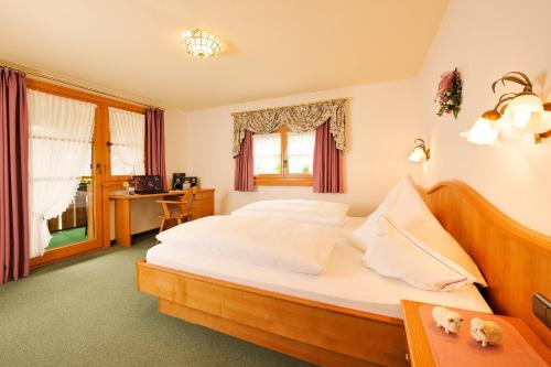 a bedroom with a large bed and a desk at Hotel Alpenblick in Fischen