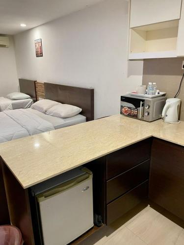 a room with two beds and a kitchen with a counter at Crystal Studio Apartment KBCP in Kota Bharu