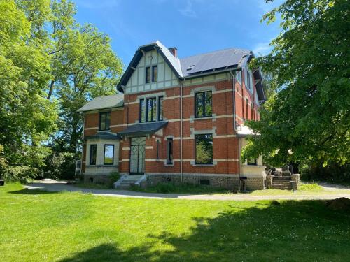 a brick house with a solar roof on a lawn at Villa Confiturerie in Braives