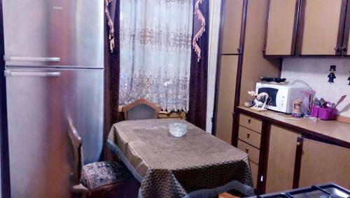 a small kitchen with a table and a refrigerator at Nova Lux Apartments in Tbilisi City