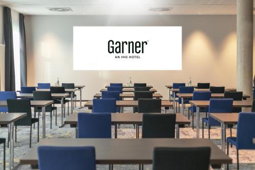 a classroom with tables and chairs and a white screen at Garner Hotel Augsburg Nord by IHG in Augsburg