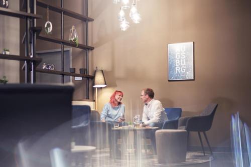 a man and woman sitting at a table in a restaurant at Garner Hotel Augsburg Nord by IHG in Augsburg