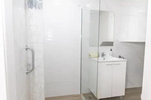 a white bathroom with a shower and a sink at Apartamento Don Guido Bajo in Barbate