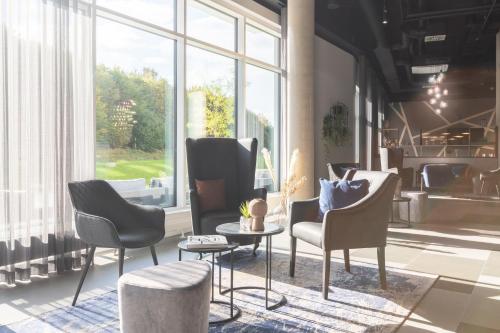 a lobby with chairs and a table and a large window at Garner Hotel Augsburg Nord by IHG in Augsburg