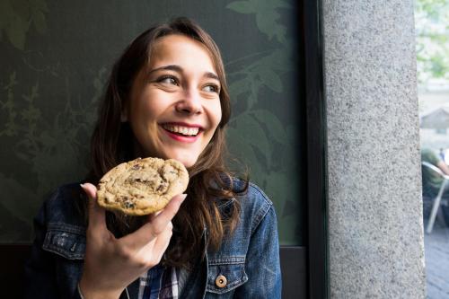 a woman is smiling while holding a cookie at Garner Hotel Augsburg Nord by IHG in Augsburg