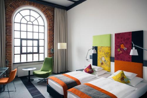 a hotel room with two beds and a green chair at Vienna House by Wyndham Andel's Lodz in Łódź