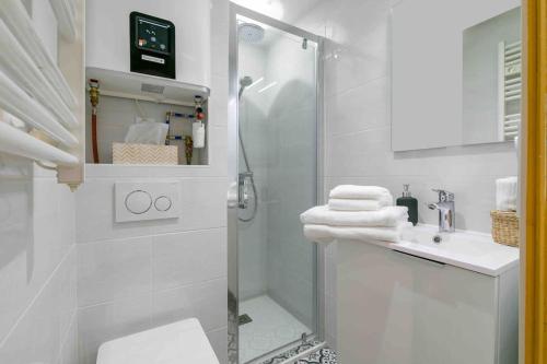 une salle de bain blanche avec une douche et un lavabo dans l'établissement Le St Nicolas au coeur du centre historique, à Dijon