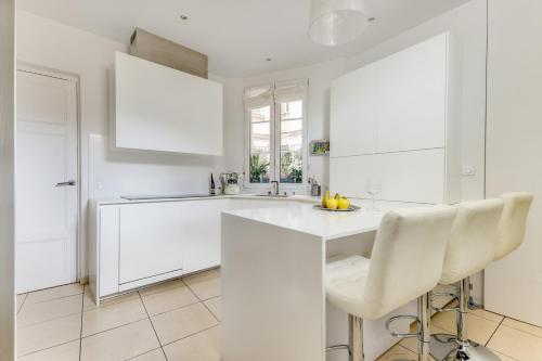 - une cuisine blanche avec comptoirs et appareils électroménagers blancs dans l'établissement Le Bridge - Elégant & Lumineux - Neuilly, à Neuilly-sur-Seine