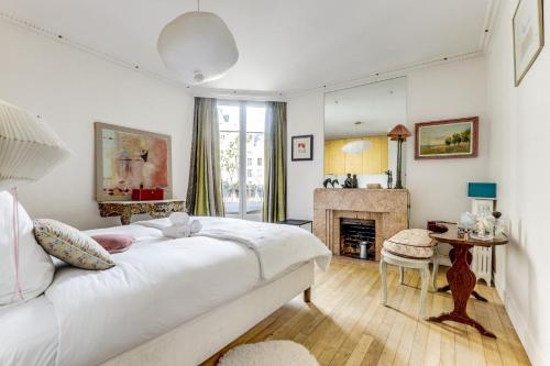 - une chambre avec un grand lit blanc et une cheminée dans l'établissement Le Bridge - Elégant & Lumineux - Neuilly, à Neuilly-sur-Seine