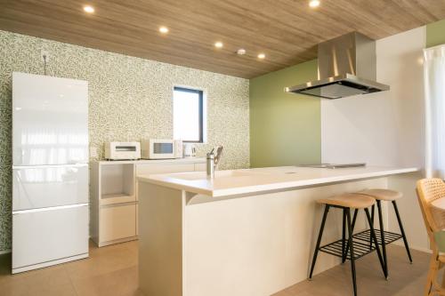a kitchen with a sink and a counter with stools at Villa Olive Myoko in Myoko
