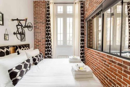 une chambre avec un lit et un mur de briques dans l'établissement M2- Modern Loft in Le Marais, Bright and Comfortable, à Paris