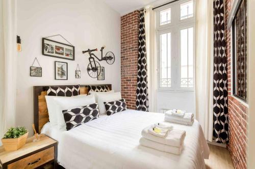 - une chambre avec un lit blanc et un vélo sur le mur dans l'établissement M2- Modern Loft in Le Marais, Bright and Comfortable, à Paris