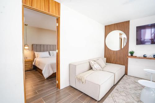 a bedroom with a bed and a white couch and a mirror at Bungalow Cajititlan Perfect for Couples in Cajititlán