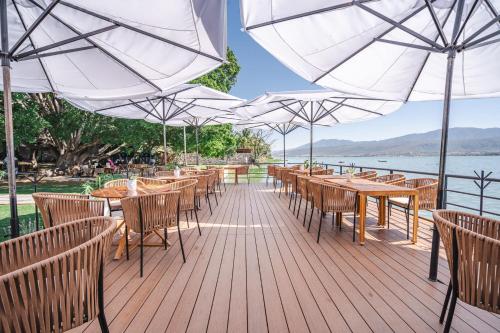 a wooden deck with tables and chairs and umbrellas at Bungalow Cajititlan Perfect for Couples in Cajititlán