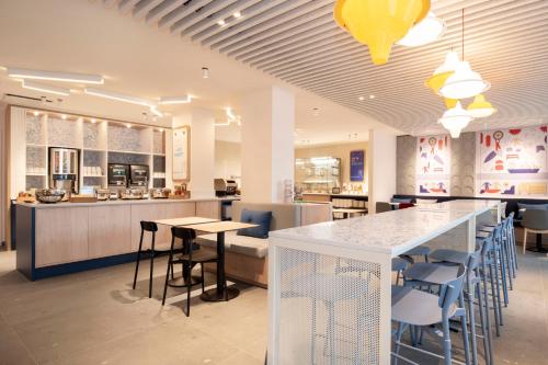 a restaurant with a bar with chairs and a counter at Holiday Inn Express & Suites Ghent by IHG in Ghent