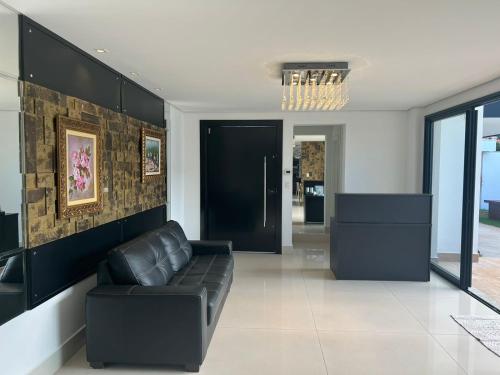 a living room with a black leather couch and a door at Ziza Hospedagem in Maringá