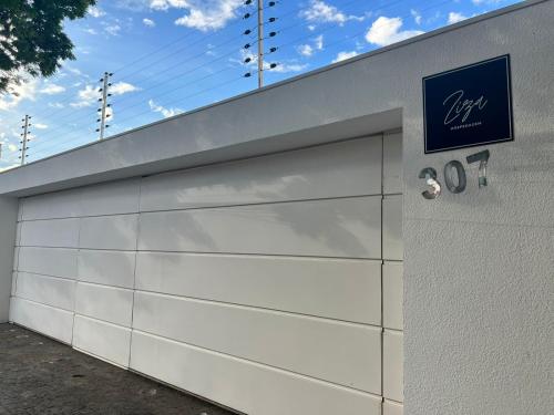 a white garage door with a sign on it at Ziza Hospedagem in Maringá
