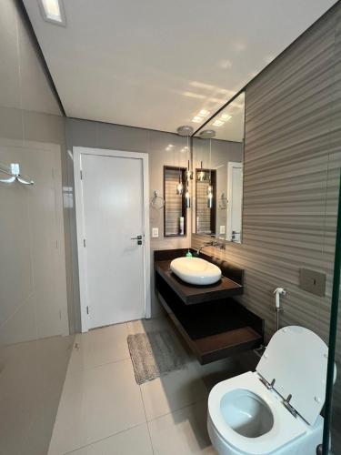 a bathroom with a toilet and a sink and a mirror at Ziza Hospedagem in Maringá