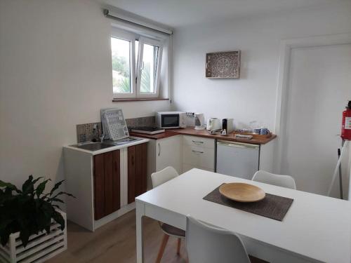a kitchen with a white table and a white table and chairs at La Finca de Ananás - Suite privada con entrada independiente in Ponta Delgada