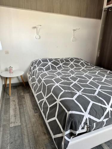 - un lit avec une couette en noir et blanc dans une chambre dans l'établissement Coup de coeur au bord du lac, à Leucate-Plage