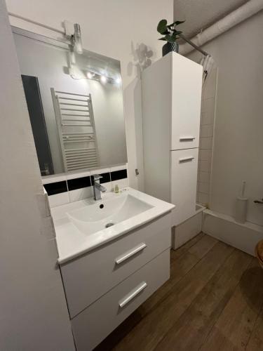 une salle de bain blanche avec un lavabo et un miroir dans l'établissement Studio Factory Loft, à La Grande Motte