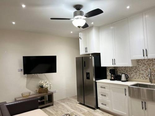 a kitchen with white cabinets and a black refrigerator at Phoenix Apartments in Calliste Land Settlement