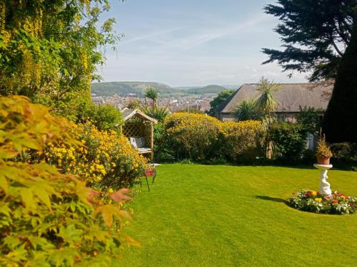 a garden with flowers and a white vase in the grass at Bron Orme Private Hotel in Llandudno