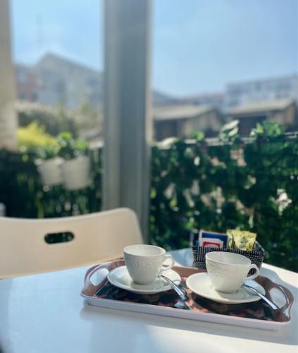 a tray with two cups and saucers on a table at Milan Cozy Apartment Gambara - SanSiro in Milan
