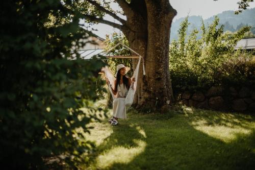 a girl standing in a swing under a tree at Hotel Gailtaler Hof in Kötschach