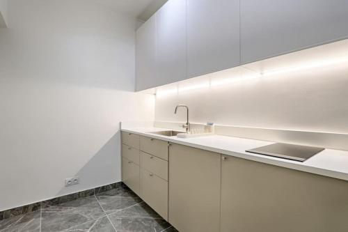 une cuisine blanche avec des armoires blanches et un évier dans l'établissement Buttes Chaumont Charming Apartment 4P, à Paris