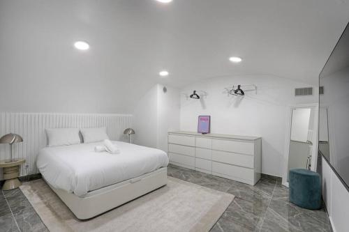 - une chambre blanche avec un lit, une commode et un miroir dans l'établissement Buttes Chaumont Charming Apartment 4P, à Paris