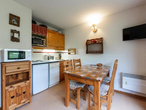 une cuisine avec une table et des chaises et un micro-ondes dans l'établissement Les Eterlous - 8 - Appt Montagne 4-6 pers, à Morillon