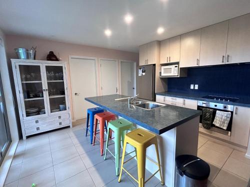 a kitchen with a counter with colorful stools in it at Waihi Wonder - Waihi Holiday Home in Waihi Beach
