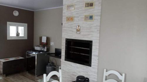 a living room with a fireplace with a stone wall at Casa verão 2025 in Tramandaí