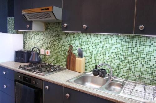 a kitchen counter with a sink and a stove at Stylish Digbeth Apartment, Sleeps 12 Opposite Birmingham Coach Station, perfect for large groups contractors in Birmingham