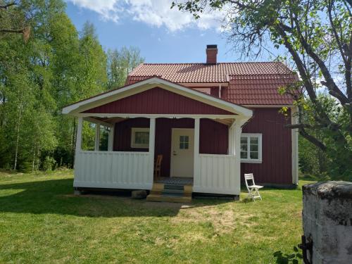 a small red house with a porch and a chair at Fäbron house in Timbonäs