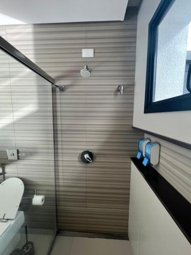 a shower with a glass door in a bathroom at Ziza Hospedagem in Maringá