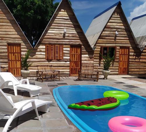 a pool in front of a log house with two frisbees at Pousada Refúgio da Marola in São Lourenço do Sul