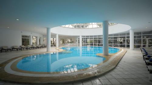a large swimming pool in a building with chairs at Royal Tulip Taj Sultan in Hammamet
