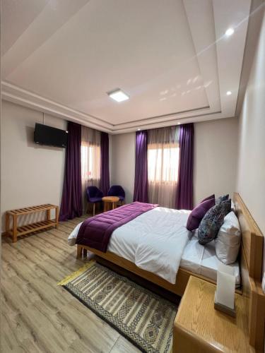 a bedroom with a large bed with purple curtains at Ferme d'hôtes Bladna Garden in Meknès