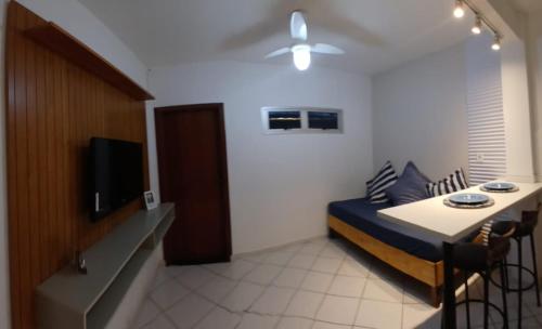 a room with a bed and a table and a tv at Apartamento em Itapuã in Vila Velha