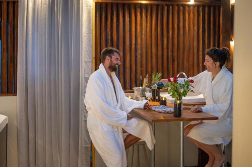 un homme et une femme assis à une table dans une salle de bain dans l'établissement Yanna Lodge, gîte classé 4 étoiles avec Spa couvert entièrement, à Arrest