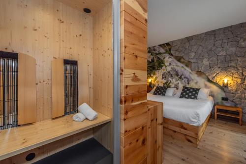a bedroom with a bed and a stone wall at Rifugio La Montanara in Molveno