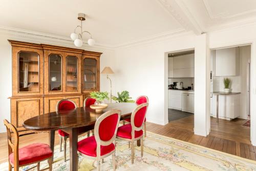 une salle à manger avec une table en bois et des chaises rouges dans l'établissement Porte Versailles 1BDR, à Paris