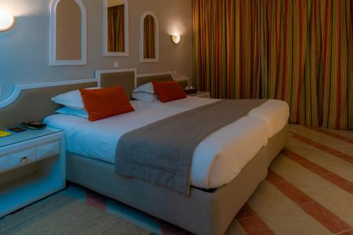 a bedroom with a large bed with orange pillows at Royal Tulip Taj Sultan in Hammamet