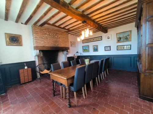 a dining room with a table and chairs and a fireplace at Maison exceptionnelle le Peyret -Vue Pyrenées-Jardin-Piscine in Serres-Castet