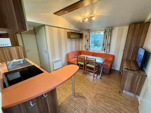 Habitación pequeña con mesa, sofá y cocina. en La Villa del Karting, en El Teso