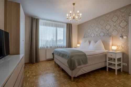 a bedroom with a bed and a television and a chandelier at WURZENBERG Hotel Lodges Südsteiermark in Gamlitz